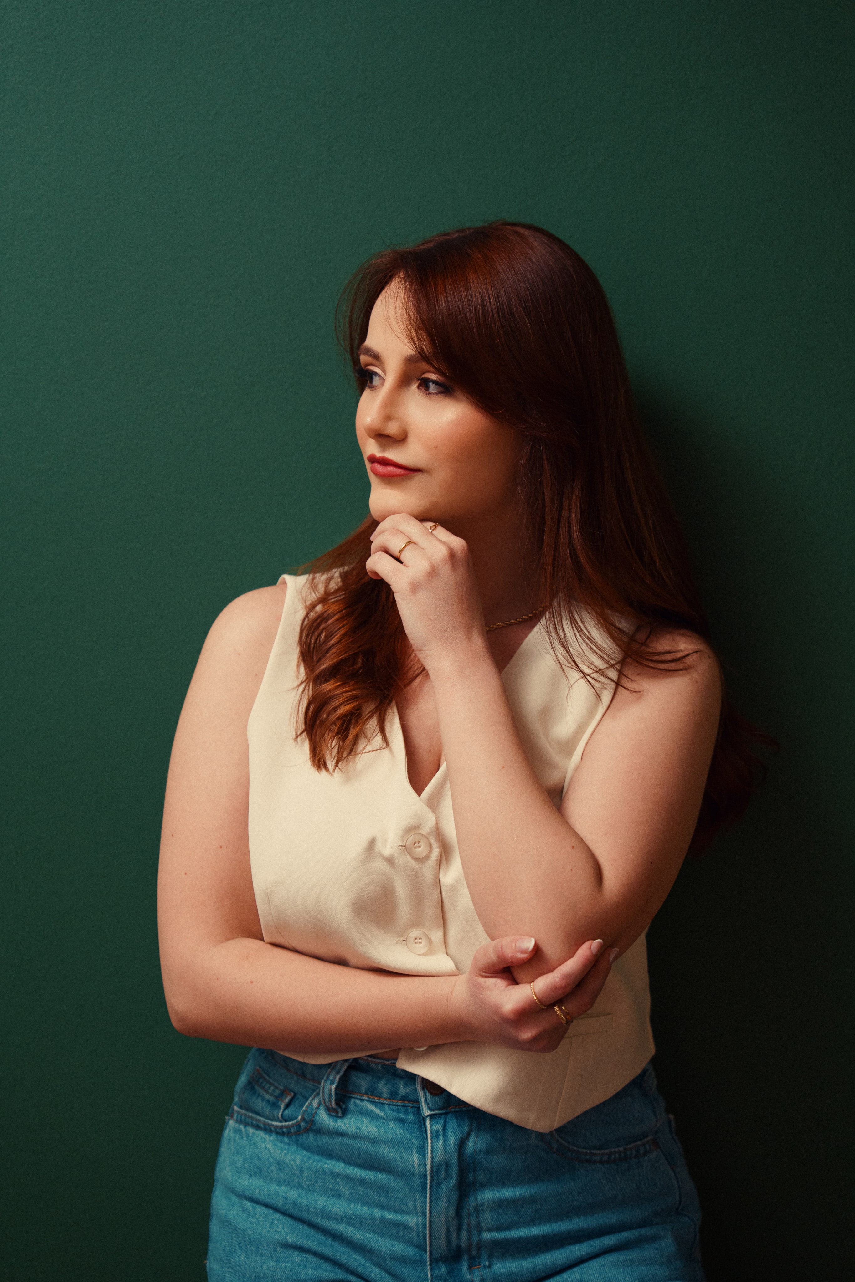 Gabrielle Alvares Milanez em pé, apoiada na parede verde